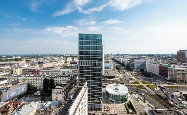 A modern high-rise building with a glass facade, surrounded by urban streets and other buildings.