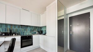 A modern kitchen with white cabinets, a black oven, and a blue-tiled backsplash. - Central Panorama Apartment | Chmielna 35 (Warszawa)