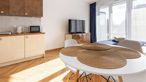 A modern kitchen with a microwave, kettle, and a flat-screen TV on a wooden counter. - Mostek Sapphire Navy Studio (Gdansk)