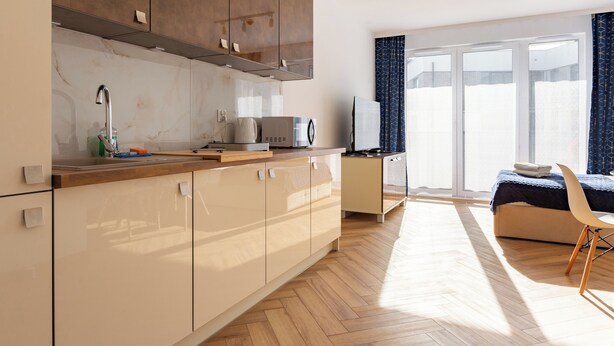 A modern kitchen with a wooden countertop, a built-in oven, and a sink. There is a dining area with a table and chairs, and a large window with curtains. - Mostek Sapphire Navy Studio (Gdansk)