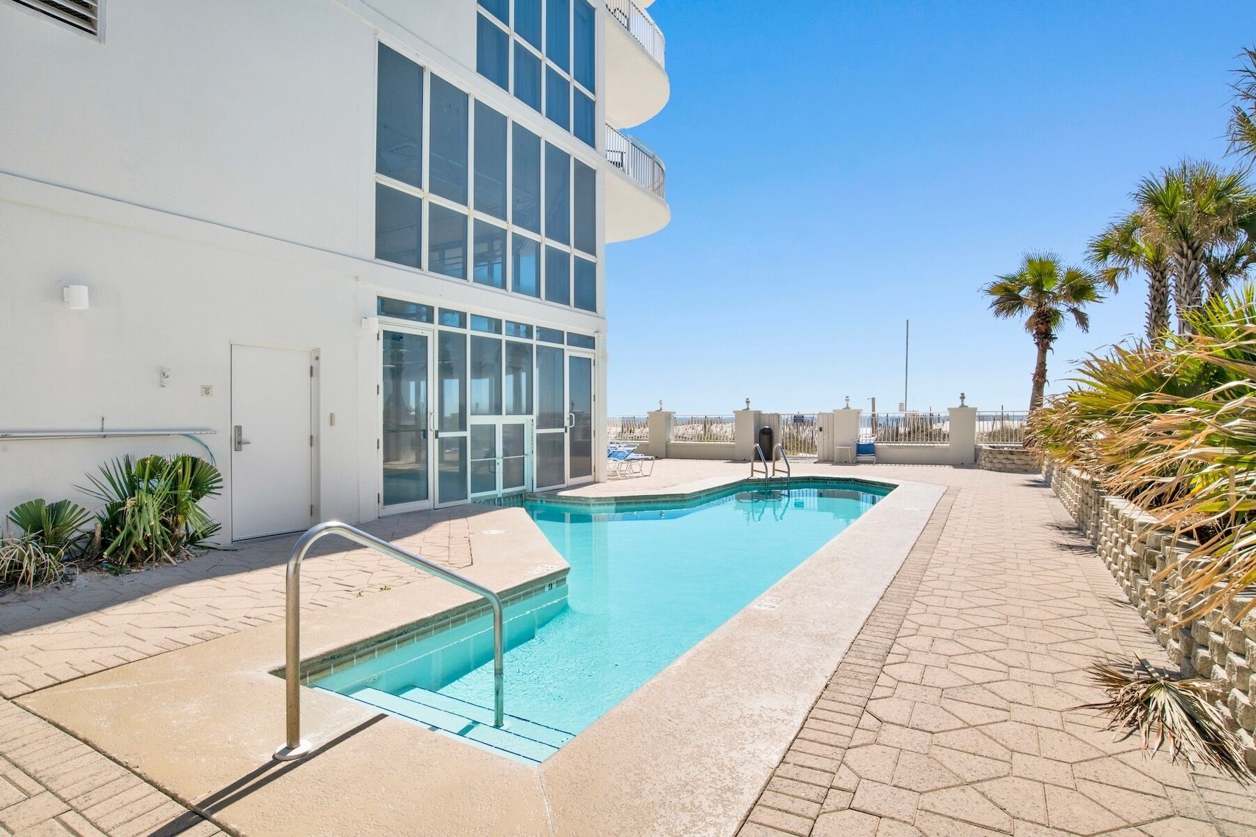 A modern hotel with a swimming pool, a covered outdoor area, and a view of the beach.