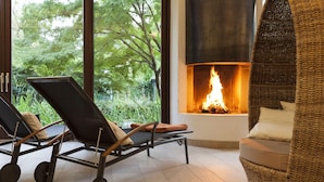 Un salon moderne doté d’une cheminée, de deux fauteuils confortables et d’un canapé en osier.