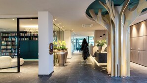Un hall d’hôtel moderne avec une allée centrale, un espace salon et une grande bibliothèque.
