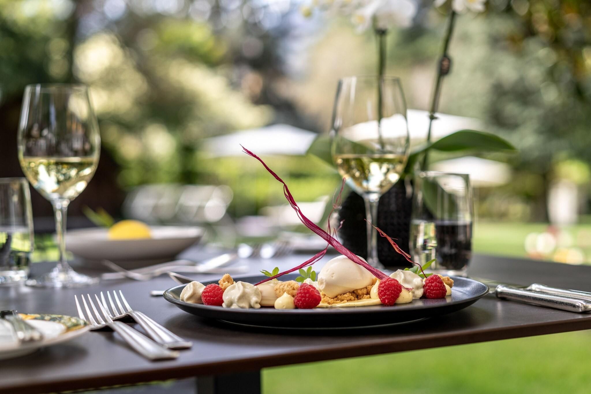 A dining table with a dessert plate, wine glasses, and cutlery.