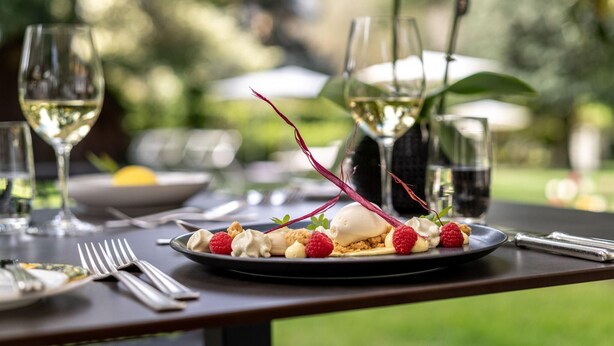 A dining table with a dessert plate, wine glasses, and cutlery. - Mignon (Merano)