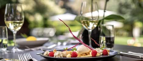 A dining table with a dessert plate, wine glasses, and cutlery.