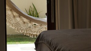 A bedroom with a bed, a view of a hammock, and a door leading outside. - Pousada Villa Recanto do Mar  (Amontada)