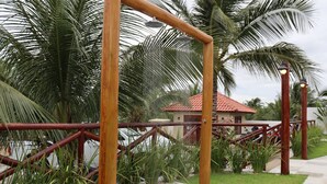 A wooden swing set with a metal frame, surrounded by palm trees and a tiled pathway. - Pousada Villa Recanto do Mar  (Amontada)