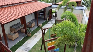 A house with a tiled roof, a patio with furniture, and a small garden. - Pousada Villa Recanto do Mar  (Amontada)