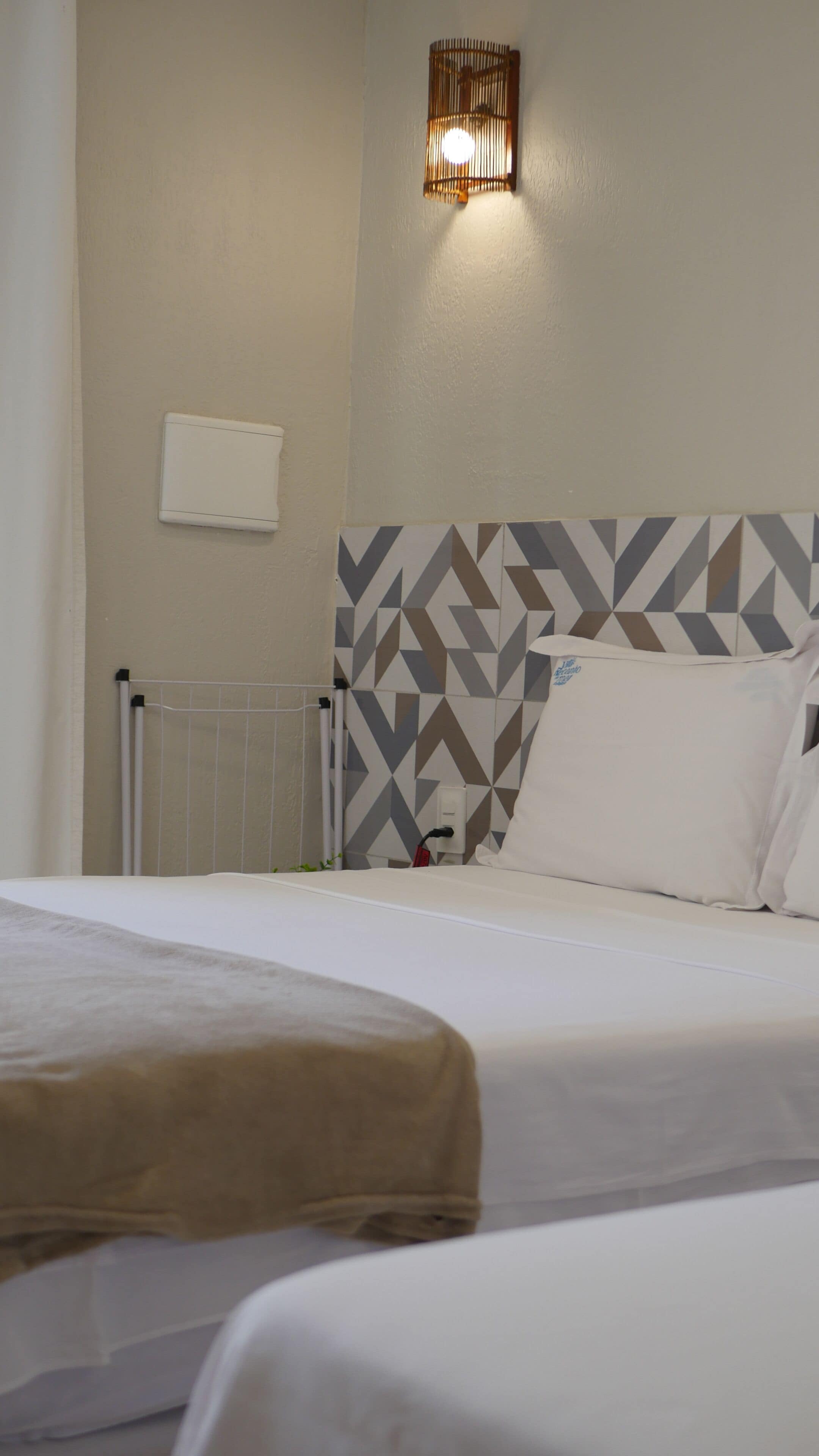 A hotel room with a bed, a wall-mounted light fixture, and a radiator.