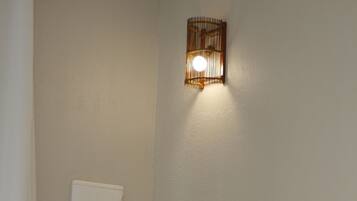 A hotel room with a bed, a wall-mounted light fixture, and a radiator.