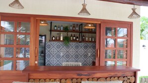 A bar area with wooden furniture, a tiled backsplash, and hanging lights. - Pousada Villa Recanto do Mar  (Amontada)