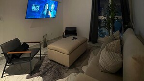 Una sala de estar moderna con una televisión de pantalla plana, un sofá, un sillón y una mesa de centro.