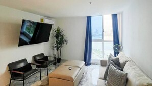 Una sala de estar moderna con un televisor de pantalla plana, un sofá, una mesa de centro y una planta en maceta.