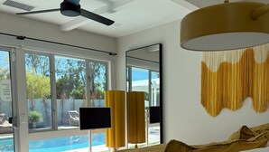 A modern bedroom with a large bed, a ceiling fan, and a view of a swimming pool.