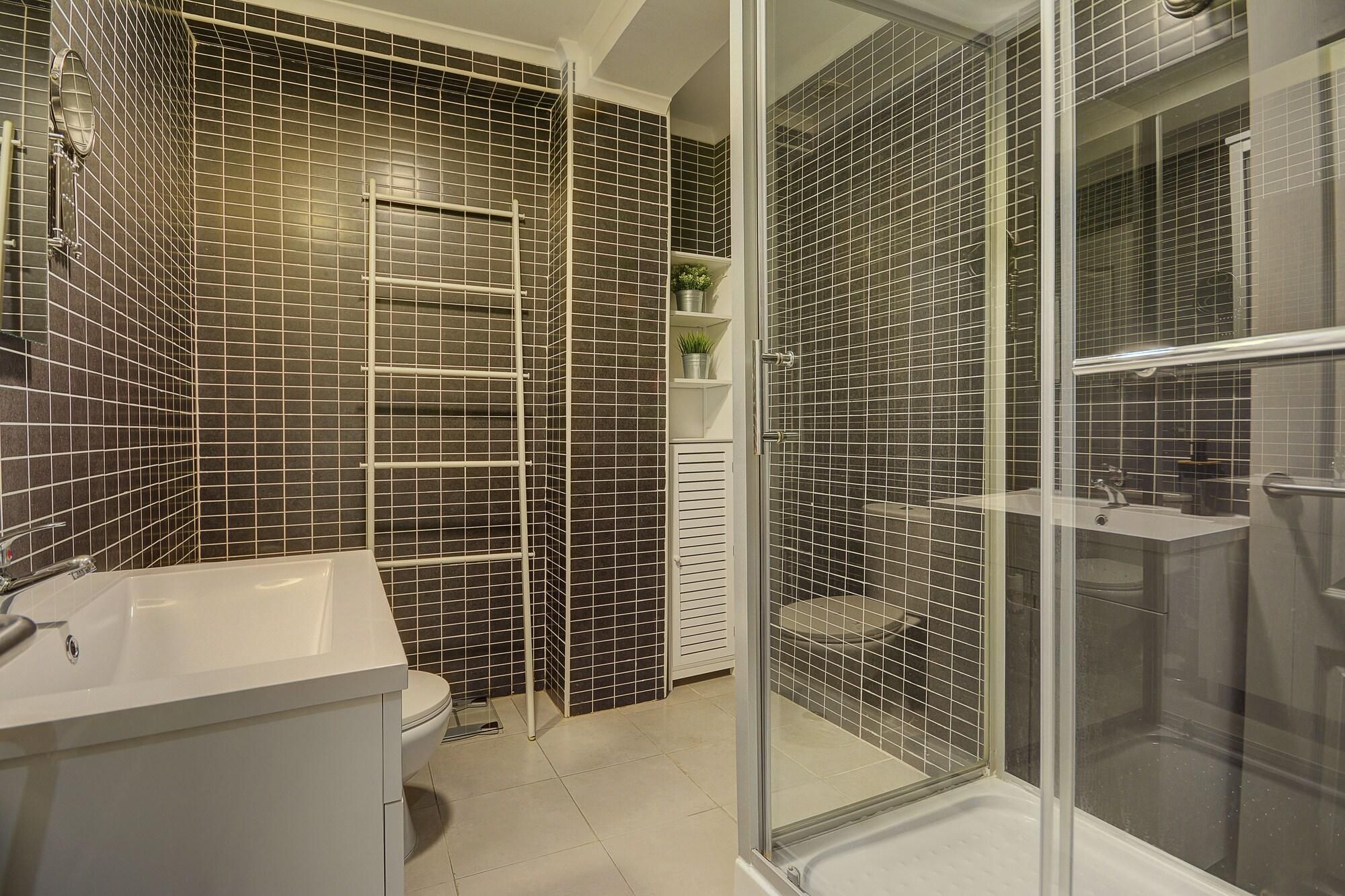 A modern bathroom with a shower enclosure, a toilet, and a sink.
