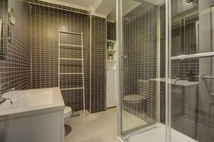 Un baño moderno con cabina de ducha, inodoro y lavamanos.