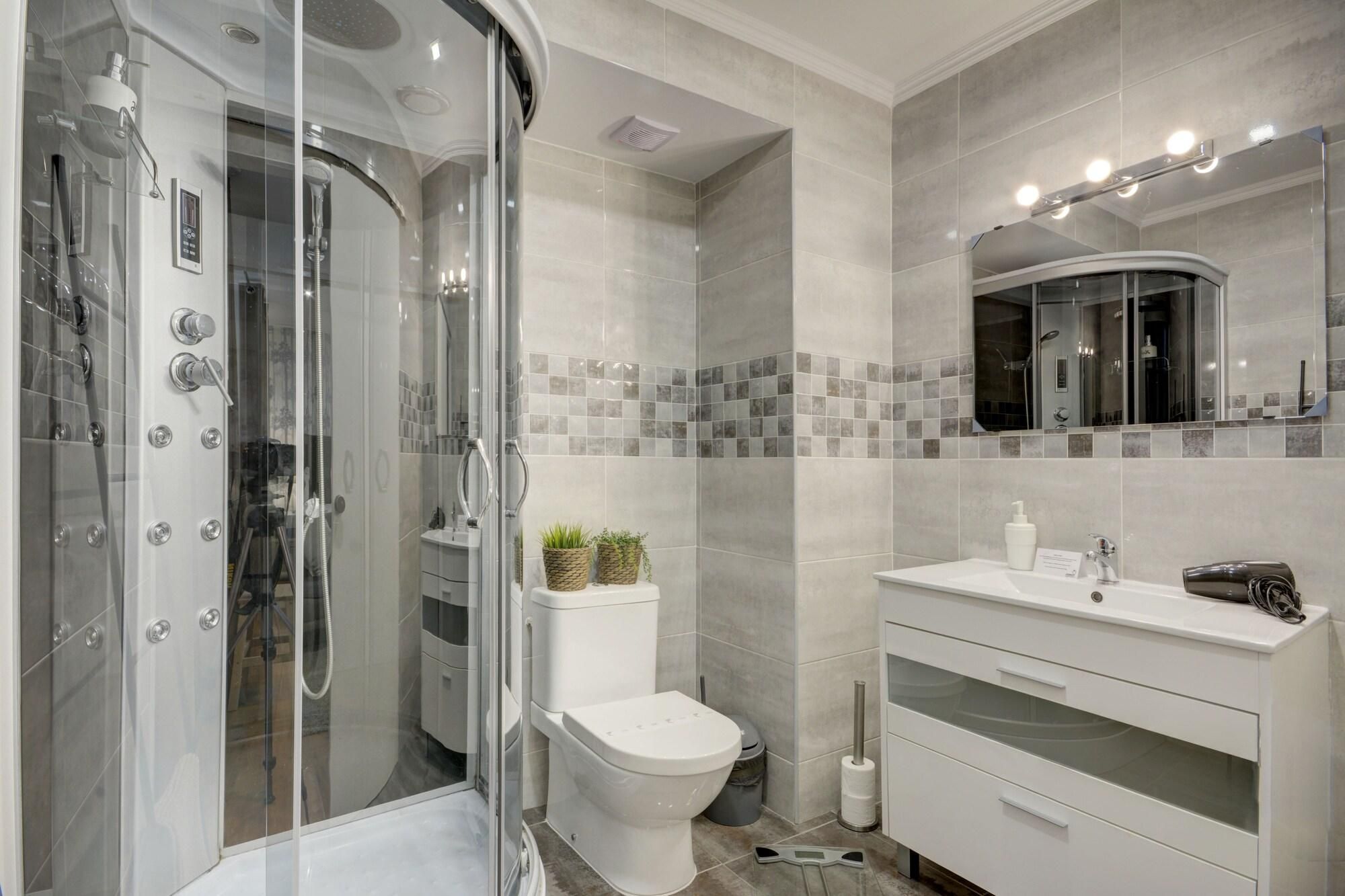 A modern bathroom with a glass-enclosed shower, a toilet, and a vanity with a mirror.
