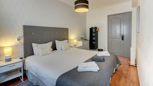 Une chambre d’hôtel moderne avec un grand lit, des tables de chevet, une armoire et une porte.