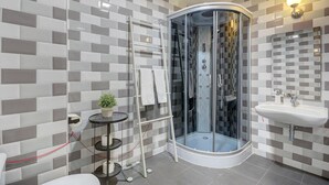 A modern bathroom with a glass-enclosed shower, a white sink, and a tiled backsplash.