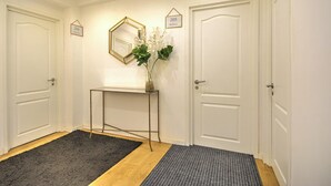 A hallway with two white doors, a small console table with a mirror, and a plant.