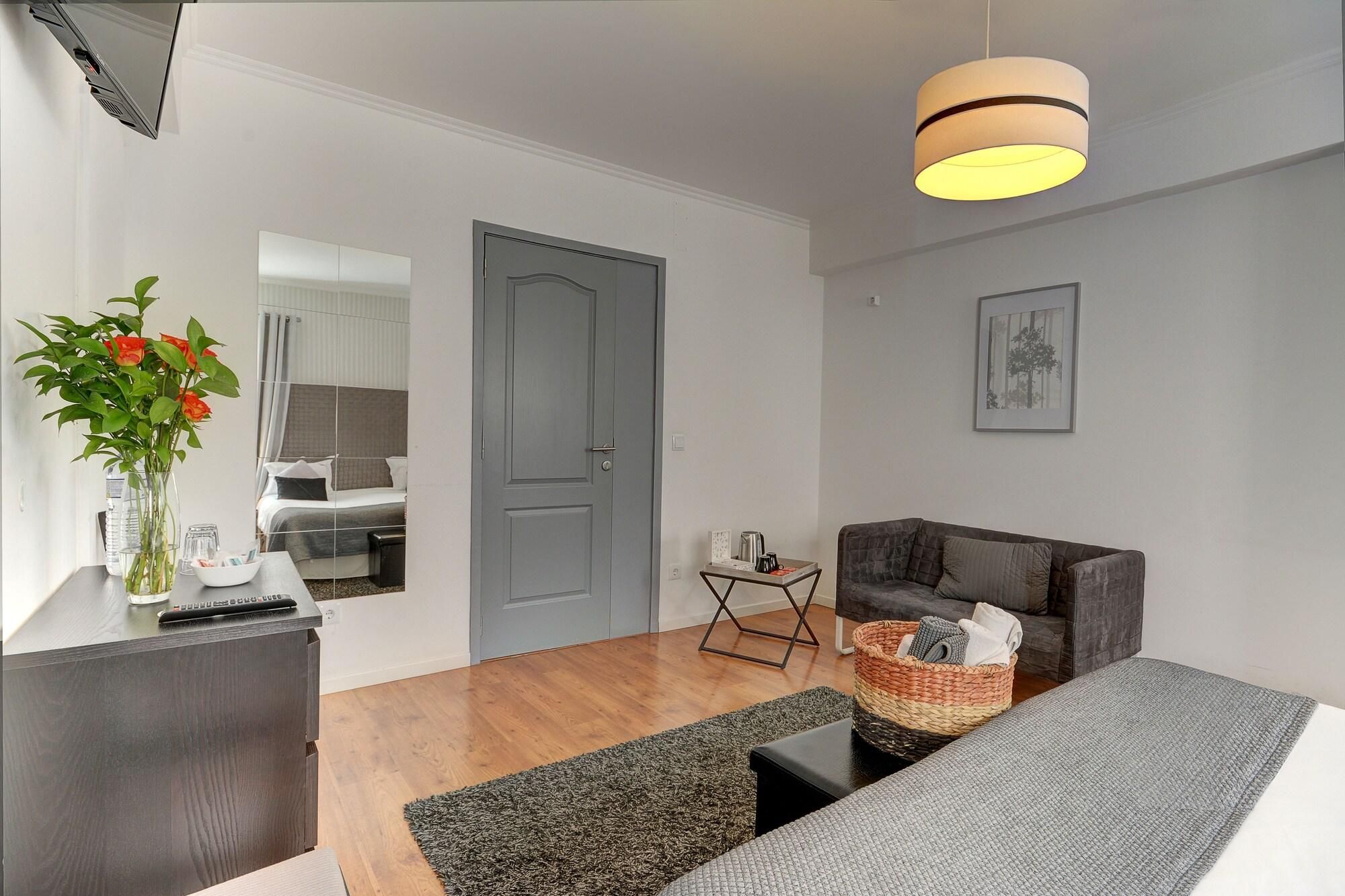 A modern living room with a grey sofa, a coffee table, a side table with a basket, and a grey door.