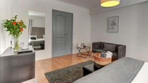 Un salon moderne avec un canapé gris, une table basse, une table d’appoint avec un panier, et une porte grise.