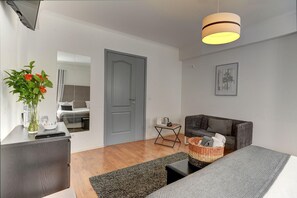 Una sala de estar moderna con un sofá gris, una mesita de centro, una mesita auxiliar con una cesta y una puerta gris.