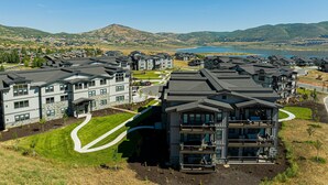 Una zona residencial con edificios modernos de varios pisos, un camino serpenteante y un lago al fondo.