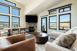 A spacious living area with a fireplace, large windows, and a view of the landscape.