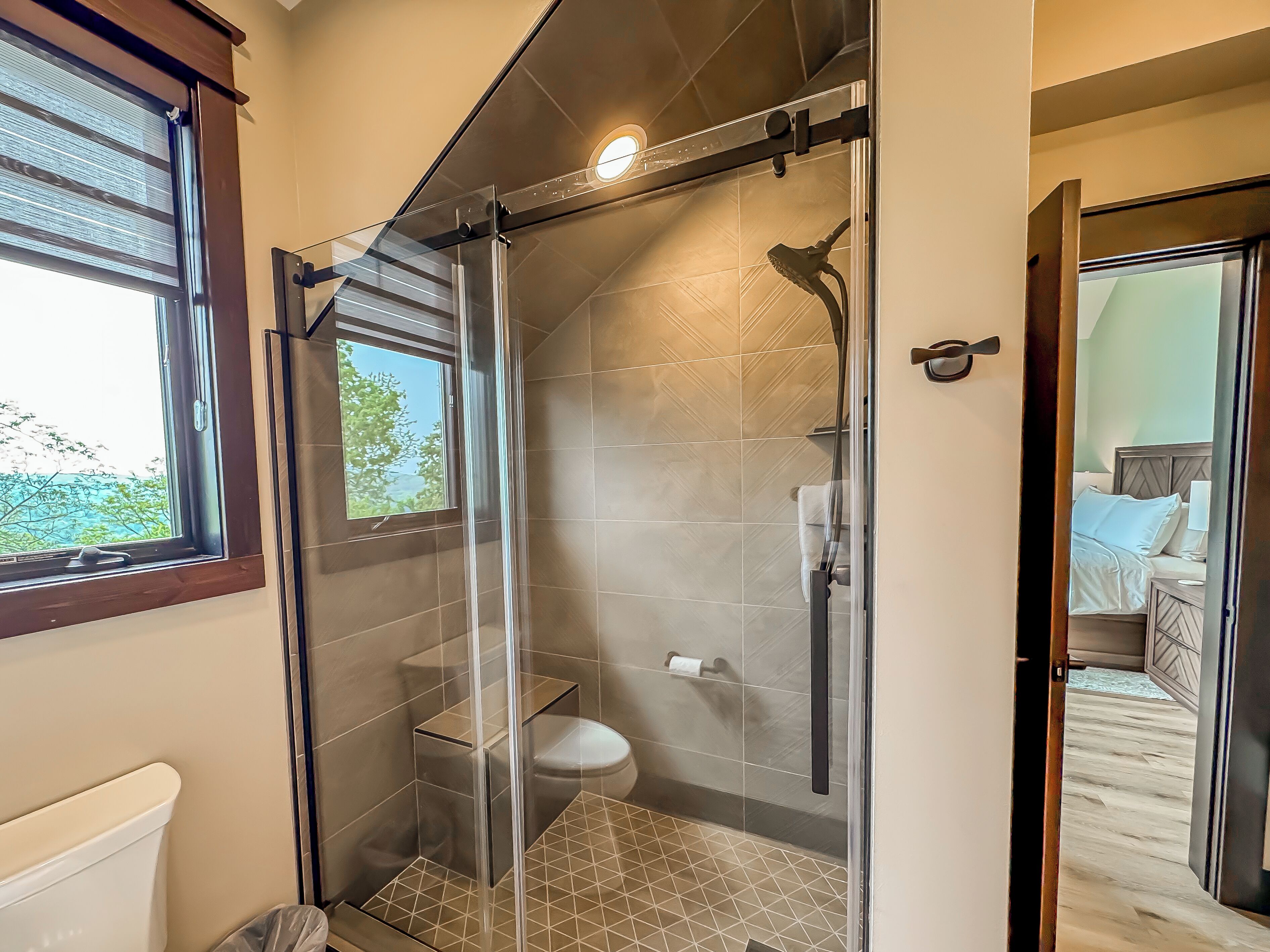 Un bagno moderno con doccia vetrata, un water e una finestra.