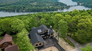 A large house with a spacious driveway and a view of a river and mountains. - New + Stunning + Luxury! Lake Access Home + Community Pool! (McHenry)