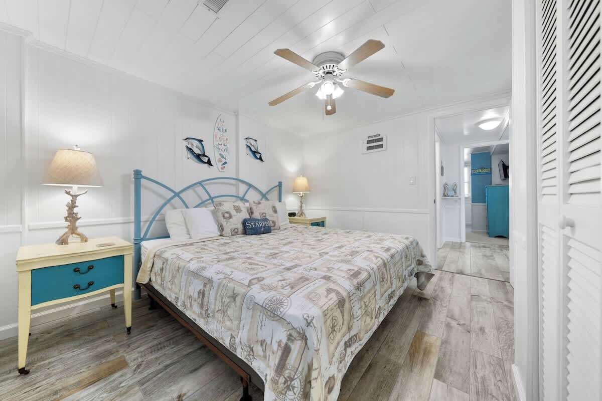 A bedroom with a bed, a ceiling fan, a nightstand, and a lamp.