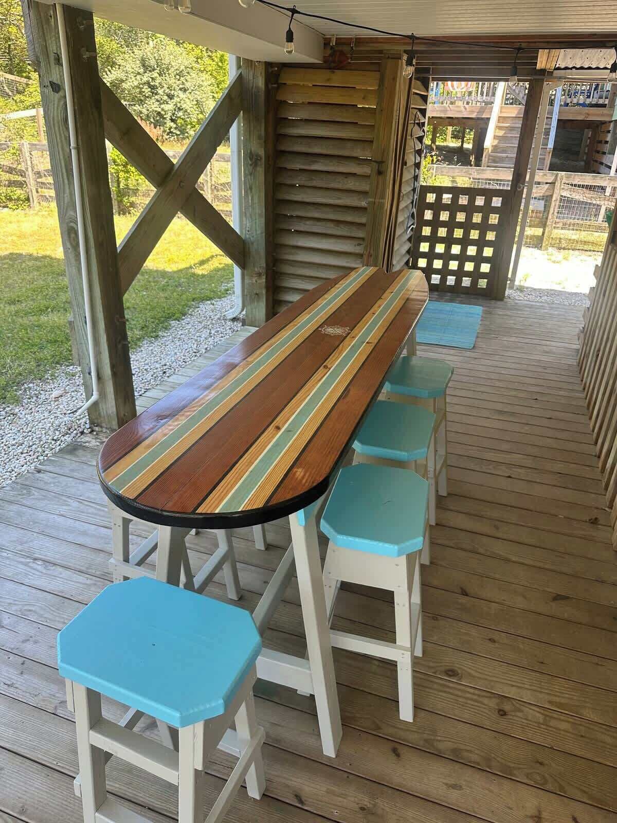 A wooden deck with a long table and matching stools.