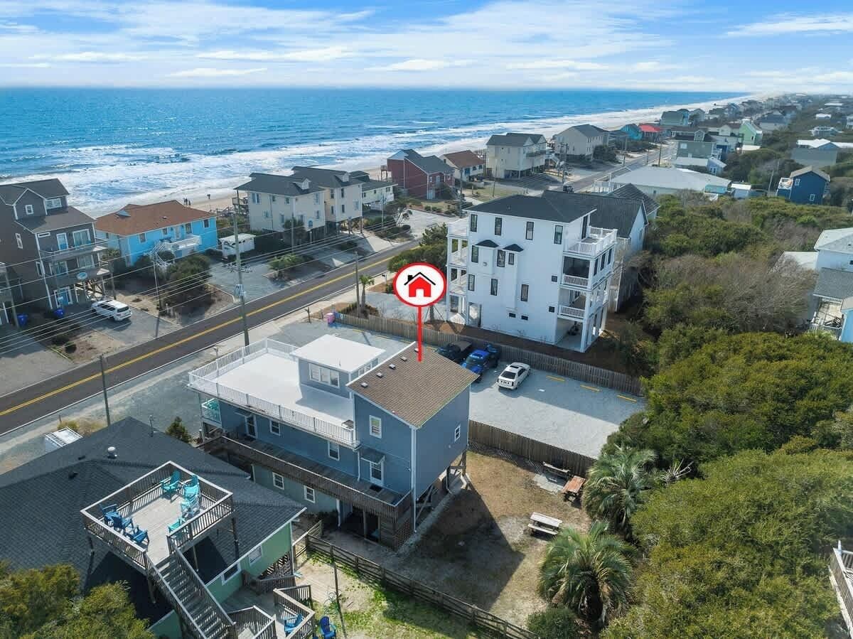 Une zone résidentielle côtière avec des maisons, une route et une plage en arrière-plan.
