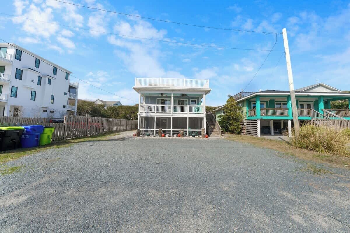 A two-story building with a balcony, a gravel driveway, and a wooden fence.