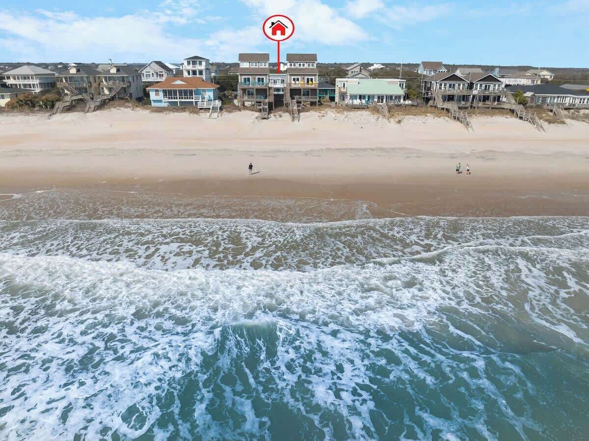 A beachfront property with multiple houses, a beach, and waves.