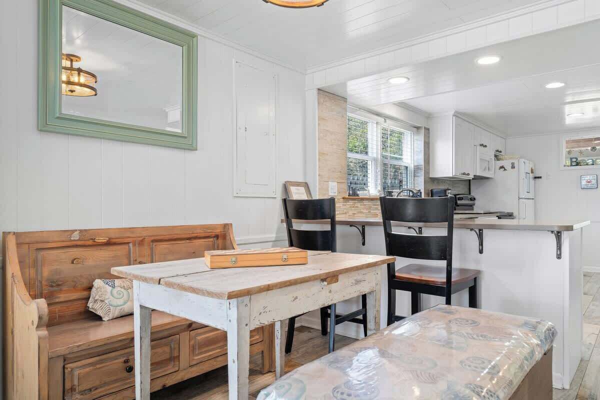 A kitchen with white cabinets, a wooden bench, a table, and chairs.