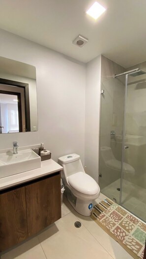 Une salle de bain moderne avec une douche à parois de verre, un lavabo blanc et des toilettes.