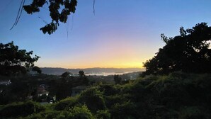 A sunset view with a clear sky, trees, and distant city lights. - 1 Bed in Shared Dorm - Backpackers Hoatel Montego Bay AC, Fan & hot water (Montego Bay)