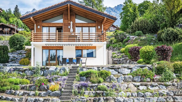 A modern chalet with a wooden exterior, a balcony, and a stone staircase leading to the entrance. - Le Souvenir by Interhome (Ovronnaz)