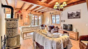 A cozy living room with a stone fireplace, wooden beams, a sofa, and a television. - Le Coeur by Interhome (Ovronnaz)