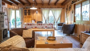A cozy wooden cabin with a dining area, a fireplace, and a comfortable seating area with a sofa and armchairs. - Le Coeur by Interhome (Ovronnaz)