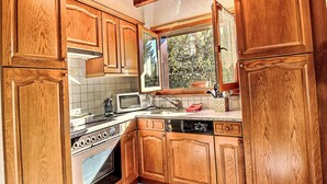 A kitchen with wooden cabinets, a microwave, a coffee maker, and a dishwasher. - Le Coeur by Interhome (Ovronnaz)