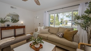 Una sala de estar con sofá, mesa de centro y ventilador de techo.