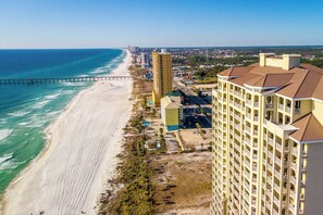 A coastal hotel with a beach view, a pier, and a high-rise building.