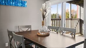 A dining area with a wooden table, white chairs, and a decorative vase with feathers. - Centrally Located Apt with Pool in Columbia, MO (Columbia)