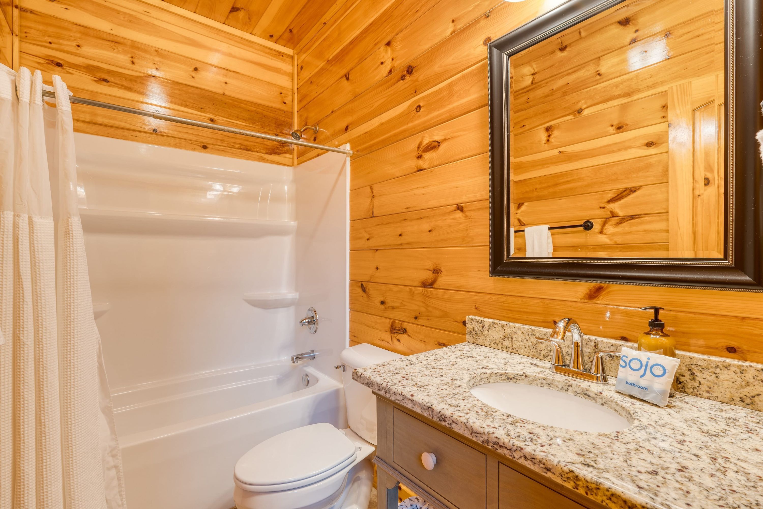 A wooden-paneled bathroom with a bathtub, toilet, and sink.
