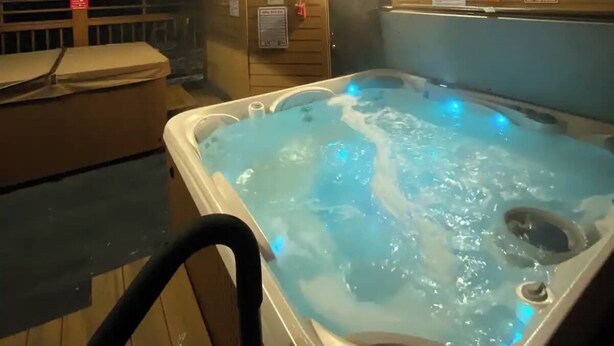 Un interior de madera con un jacuzzi, paredes de madera y un techo con iluminación empotrada.