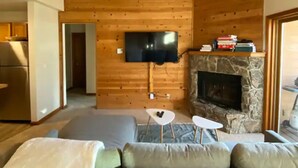 Una sala de estar moderna con chimenea de piedra, un televisor montado en la pared y una zona de estar acogedora con un sofá y una mesita de centro.